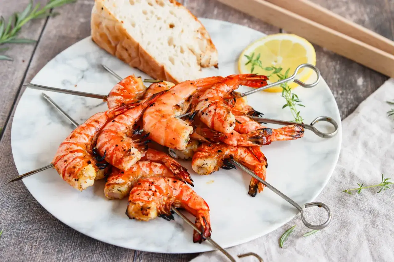 Gegrillte Garnelen auf Spie&szlig;en, bereit zum Genie&szlig;en. Mit Schale schmecken sie am besten! Dazu Brot und Zitrone.