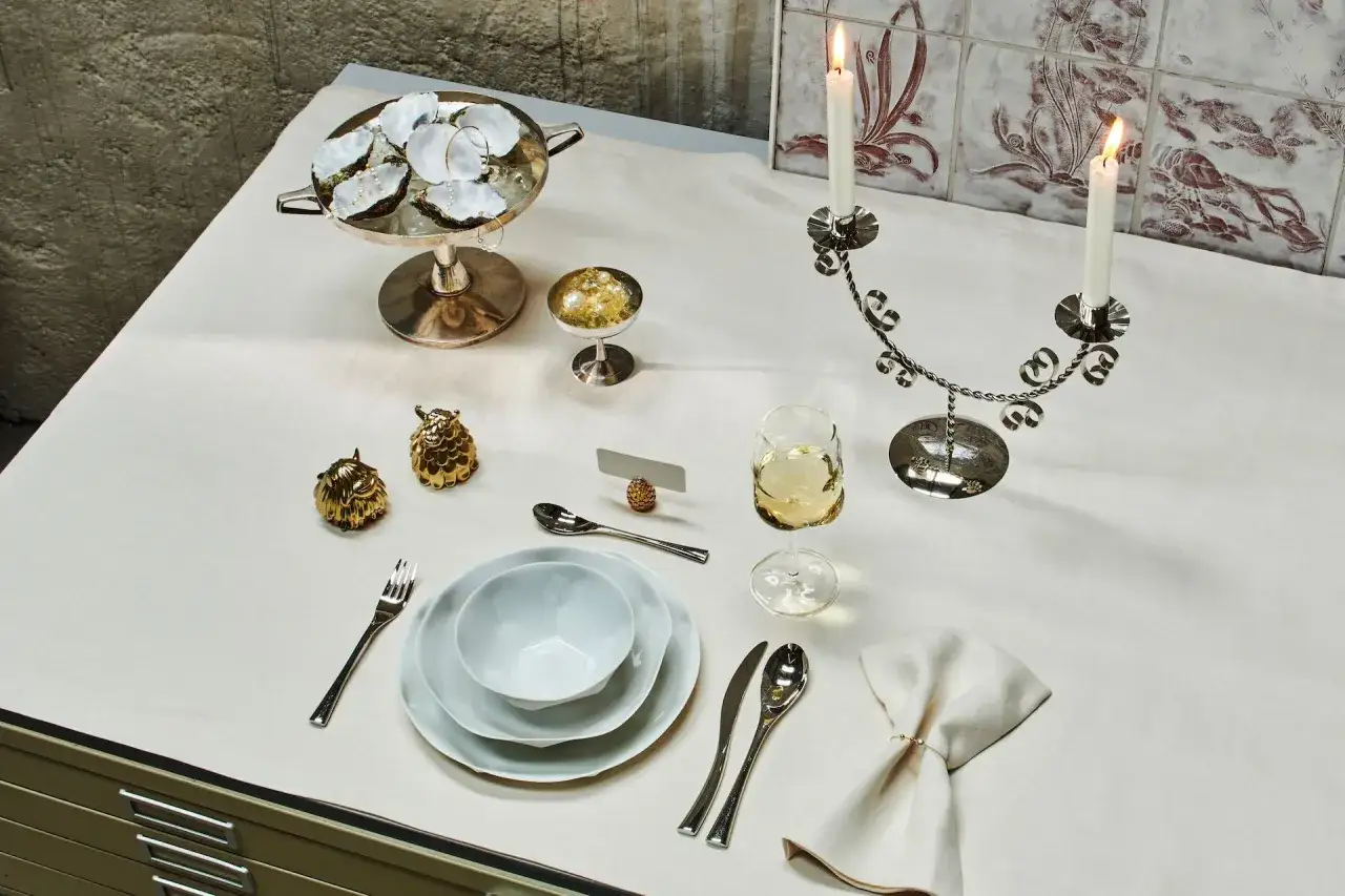 Festlich gedeckter Tisch mit Austern, Kerzen und goldenen Eulenfiguren. Ein Beispiel für Benimmregeln bei Tisch, elegant und stilvoll arrangiert.