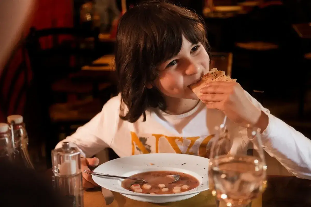Ein Junge isst genüsslich Brot, während er eine leckere Suppe isst.