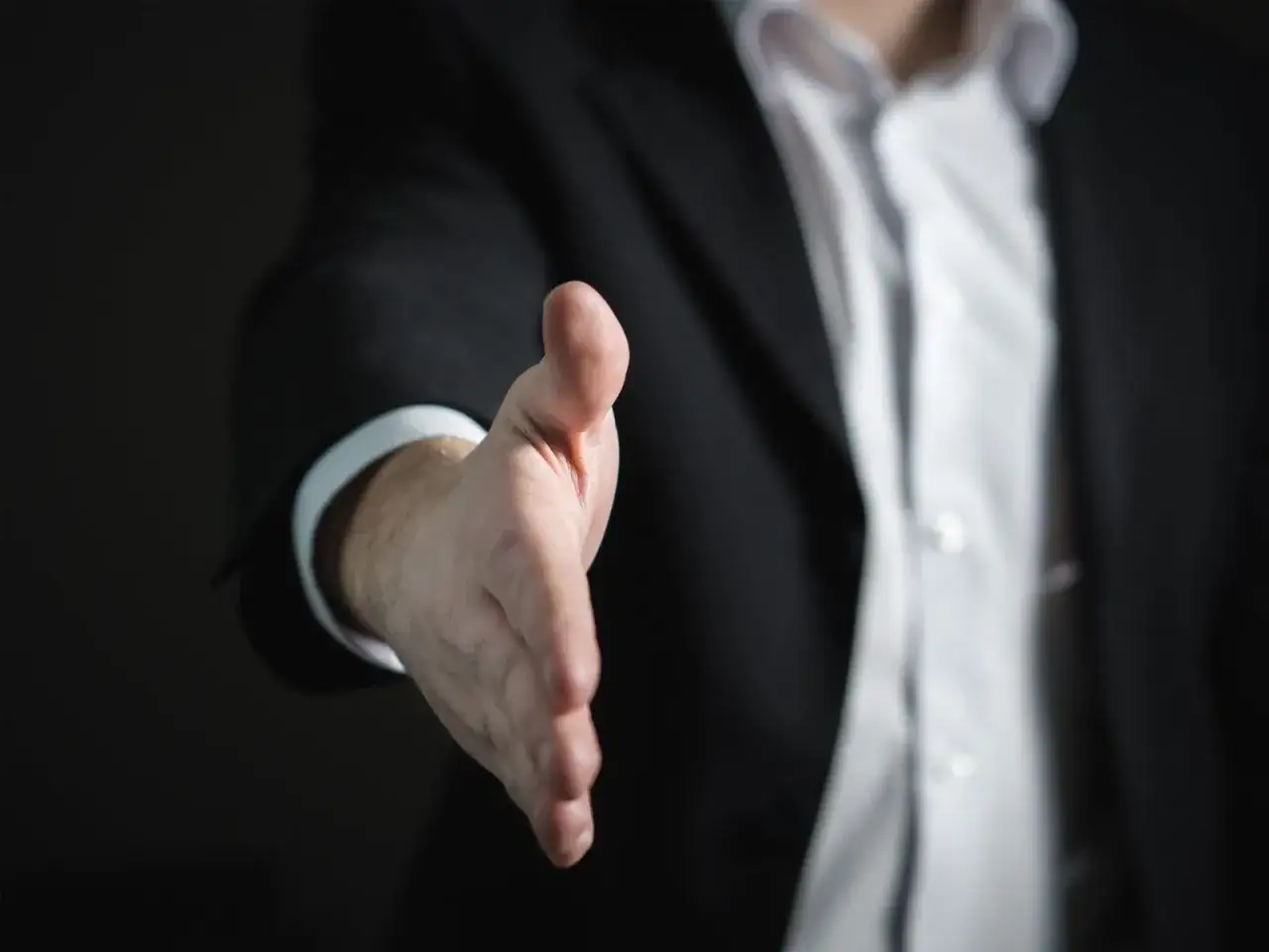 Ein Gesch&auml;ftsmann im Anzug streckt die Hand aus, um sich vorzustellen.