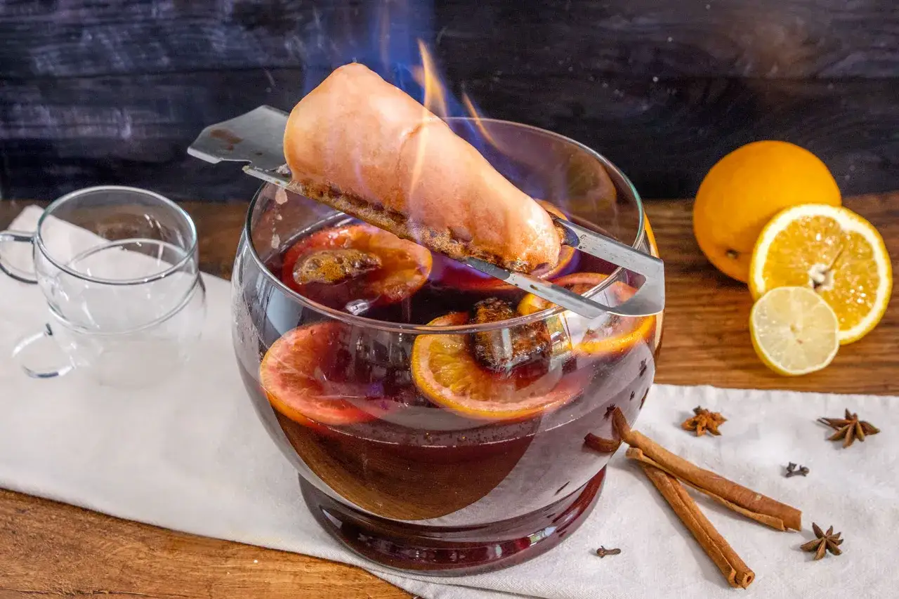 Feuerzangenbowle brennt! Ein Zuckerhut tropft gl&uuml;hend in die hei&szlig;e, orangen- und zimtduftende Bowle. So trinkt man Feuerzangenbowle.